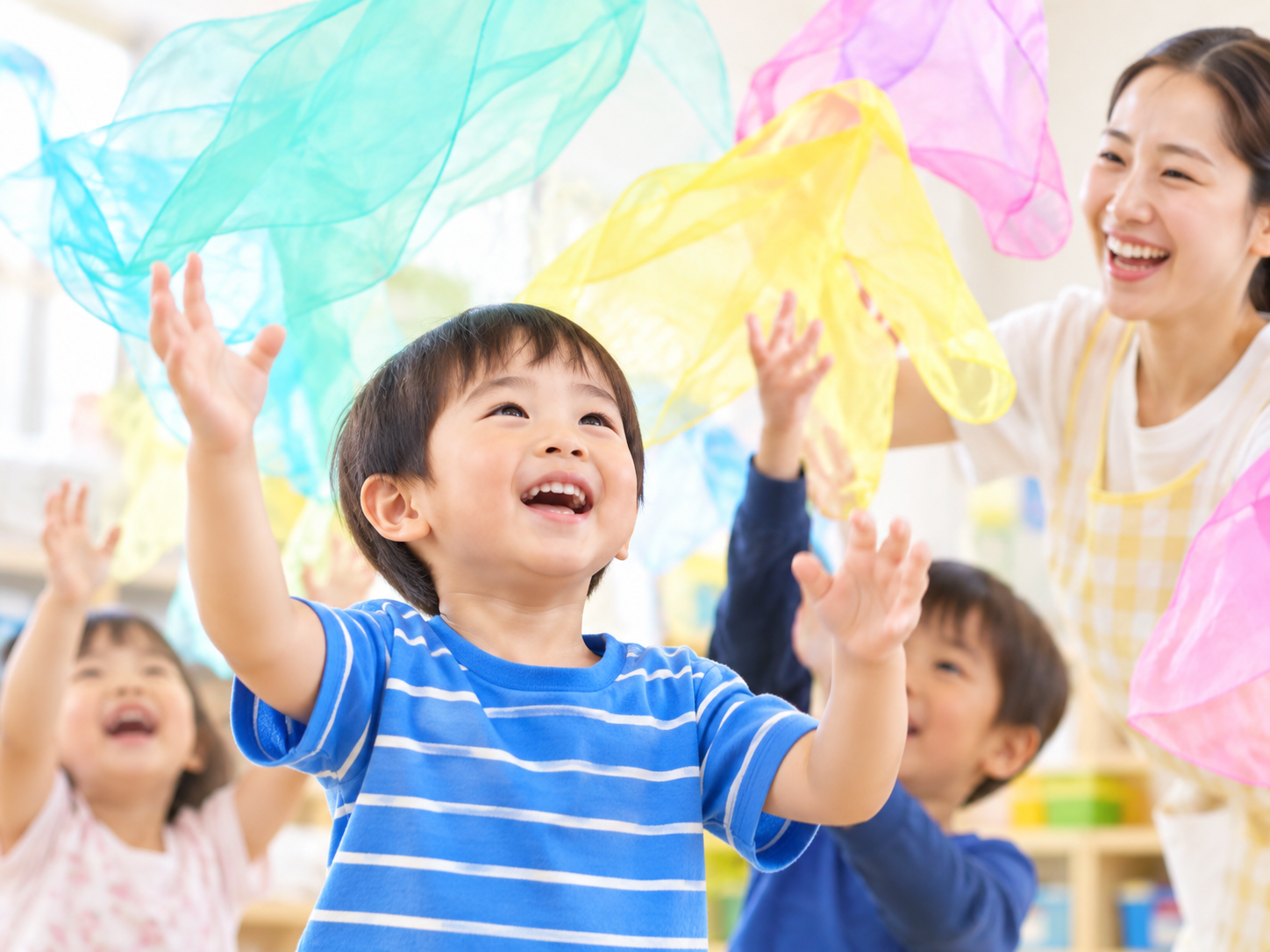 カラフルな布での遊びを楽しむ子どもと先生